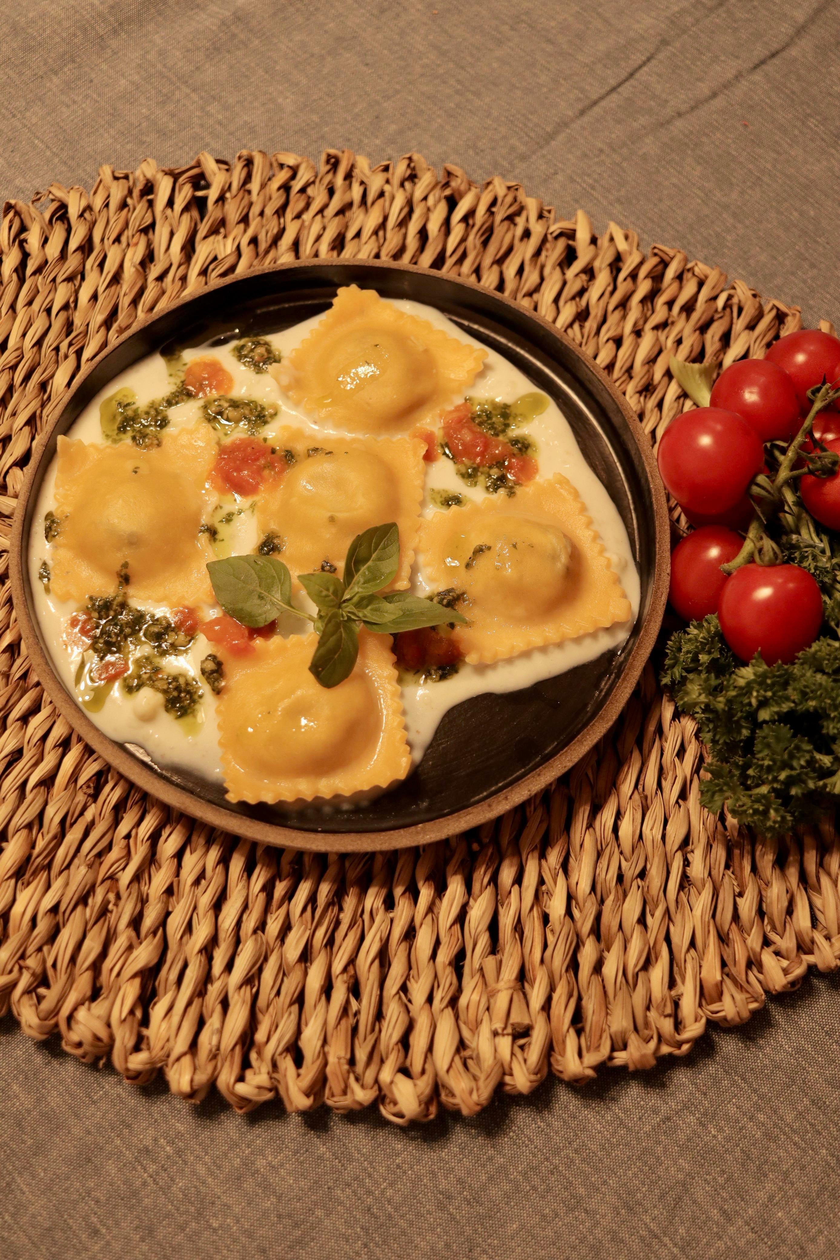 Ravioli artesanal servido com molho claro e pesto